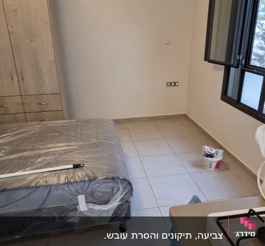 חדר בדירה מרוהטת עם כיסוי ניילון להגנה על הריהוט בזמן צביעה